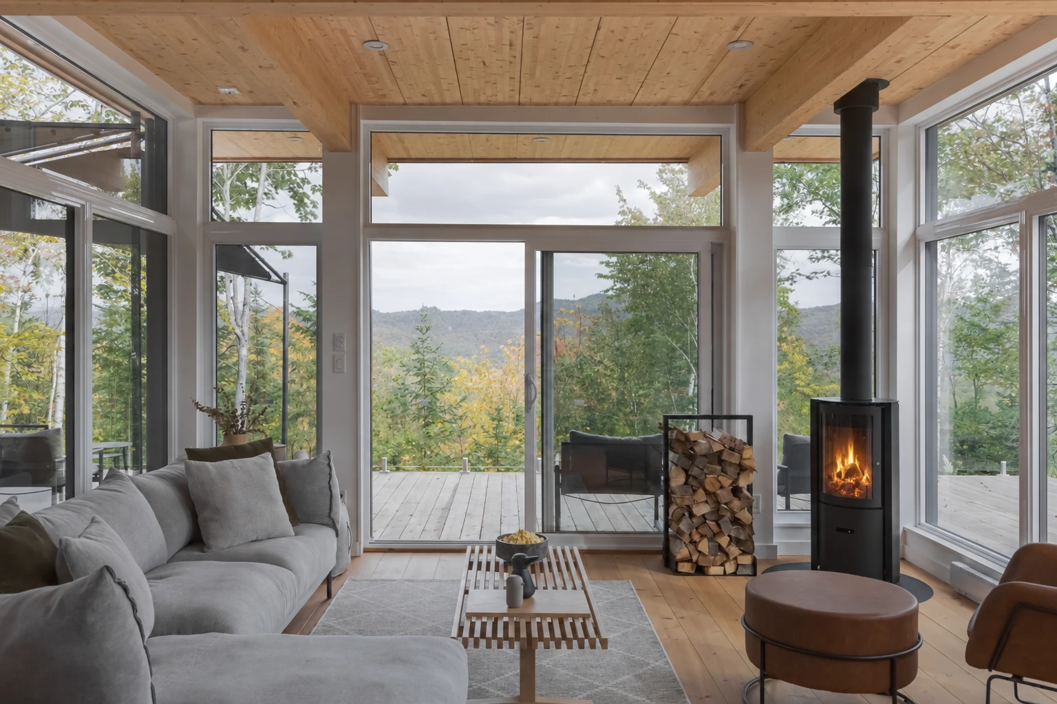 WOLM Cabin living room with floor-to-ceiling windows, mountain views, and a lit wood-burning fireplace