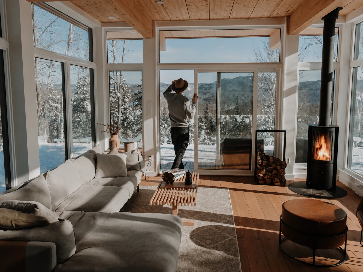 WOLM Cabin panoramic living room with snowy mountain views and the fireplace lit